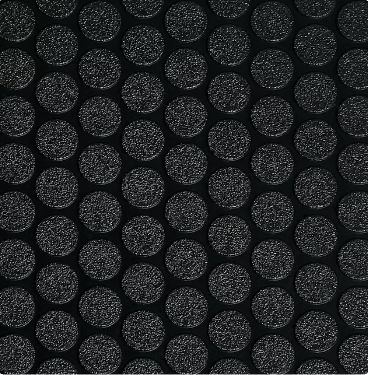 Close-up of raised coin pattern PVC garage flooring roll being installed, slip-resistant black surface